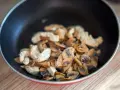 Champignons et poulet sautés dans une poêle. Une recette à éviter si vous avez une allergie champignon.