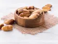 Un bol en bois rempli de noix du Brésil, mettant en avant leurs bienfaits nutritionnels. Quelques noix sont dispersées autour.