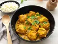Boulettes de poulet au curry, parsemées de sésame et de coriandre, servies avec du riz blanc. Une recette de riz au curry facile et savoureuse.
