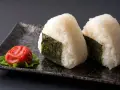 Deux onigiri algue sur une assiette avec une prune salée.