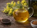 Un pichet de liquide doré, l'huile de colza cuisson, à côté de graines et de fleurs jaunes.