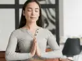 Jeune femme méditant, mains jointes, pour apprendre comment reduire le stress naturellement.