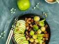 Salade colorée avec des tranches de pomme verte, des choux de Bruxelles, des dés de tofu croustillant et des noix, le tout arrosé d'une vinaigrette miso.