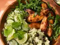 Un bol de riz au miso avec poulet glacé, concombre, coriandre, roquette et une purée verte parsemée de graines.