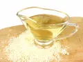 Un vinaigrier en verre rempli de liquide doré, entouré de grains de riz. Une idée pour par quoi remplacer le vinaigre de riz.
