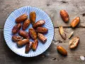 Assiette de dattes sur fond de bois. Une personne souffrant d'allergie aux dattes ne peut pas en manger.