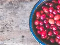 Cranberries dans un bol bleu sur fond de bois. Un remède naturel pour l'infection urinaire.