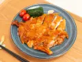 Délicieux poulet teriyaki recette, tranché et glacé, servi avec des tomates cerises et des épinards sur une assiette bleue.