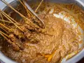 Brochettes de poulet baignant dans une généreuse sauce satay crémeuse, prêtes à être dégustées.