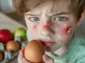 Visage d'enfant irrité, gros plan sur un œuf. Il semble souffrir d'une allergie œuf cru.