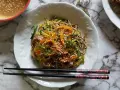 Salade de nouilles soba colorée avec des carottes, des courgettes et des graines de sésame, servie avec une sauce crémeuse.
