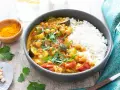 Un délicieux curry végétarien aux pois chiches, courgettes et tomates, servi avec du riz blanc et garni de coriandre fraîche.