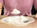 Une cuillère de riz blanc fumant, résultat d'une cuisson parfaite, est soulevée au-dessus d'une assiette remplie.