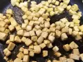 Dés cubes de tofu caramélisé dorent dans une poêle, prêts à être dégustés.