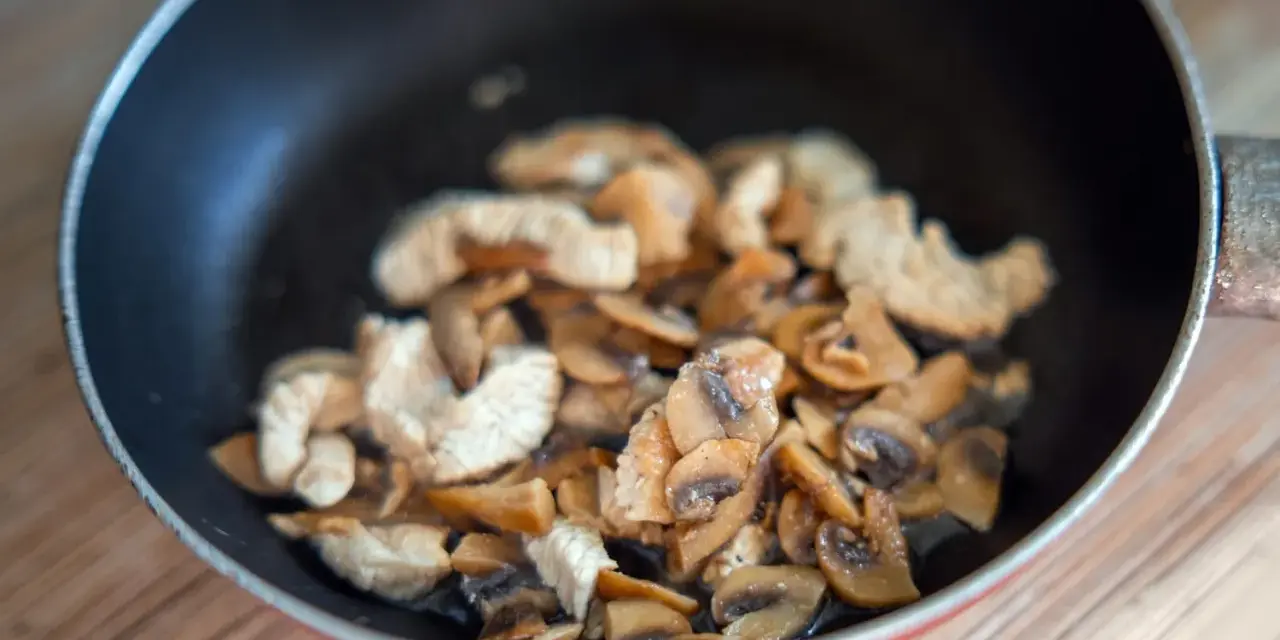 Champignons et poulet sautés dans une poêle. Une recette à éviter si vous avez une allergie champignon.