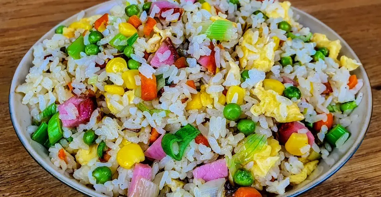 Riz cantonais coloré avec petits pois, maïs, carottes, œuf et jambon. Quelle sauce soja pour riz cantonais ? Une touche de sauce soja rehausse ce plat.