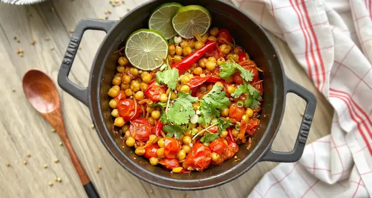 Un délicieux curry thaï végétarien aux pois chiches, tomates et coriandre, garni de quartiers de citron vert.