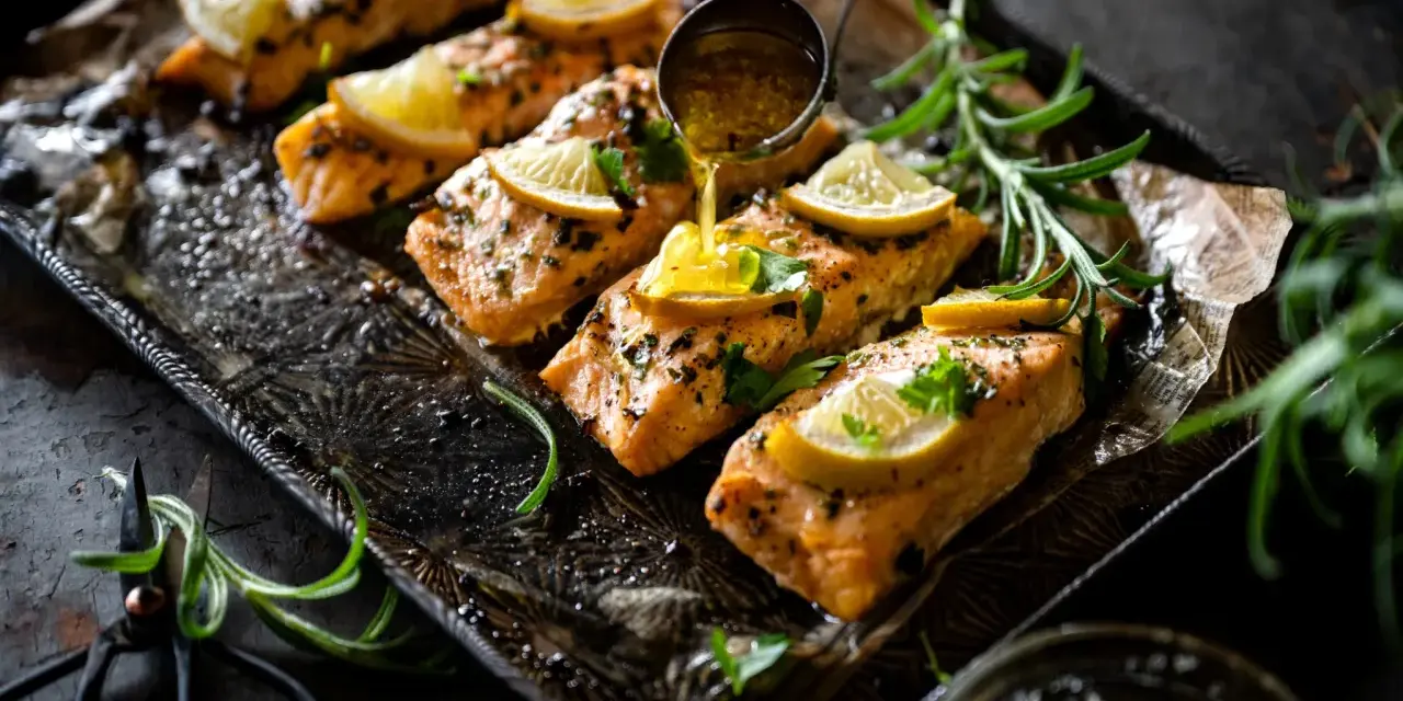 Filets de saumon sauce soja sucrée, garnis de citron et de persil, sur un plateau orné. Une louche verse la sauce.