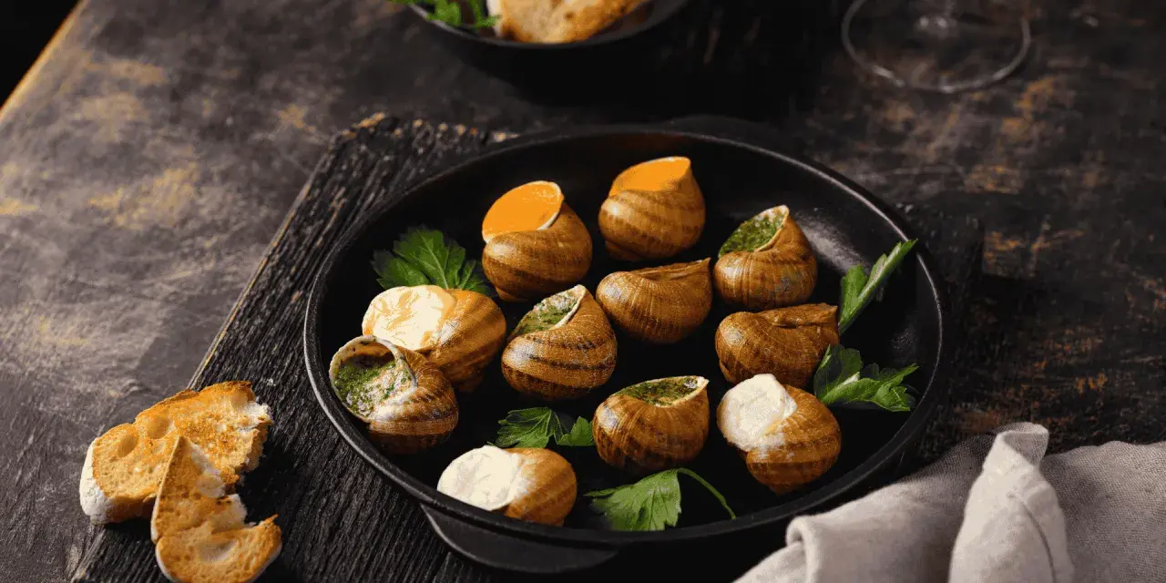 Plat d'escargots à l'ail et persil, servi avec du pain grillé. Attention, une allergie escargot peut survenir !