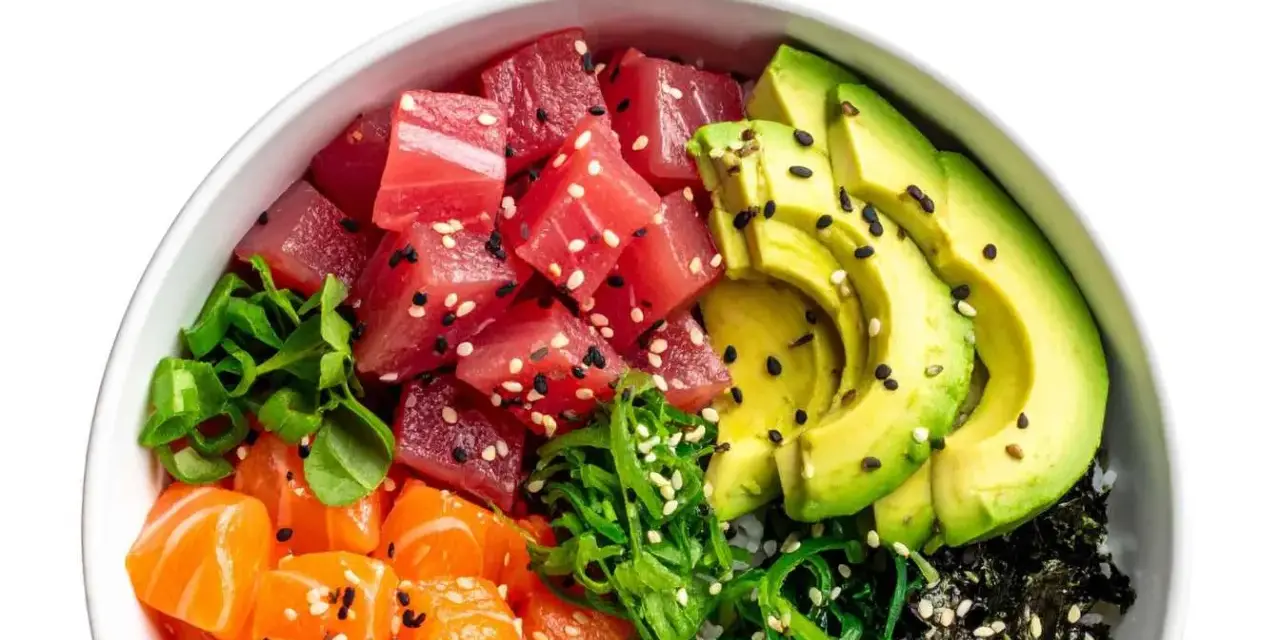 Un délicieux poke bowl avec thon, saumon, avocat, algues et sauce, garni de graines de sésame.