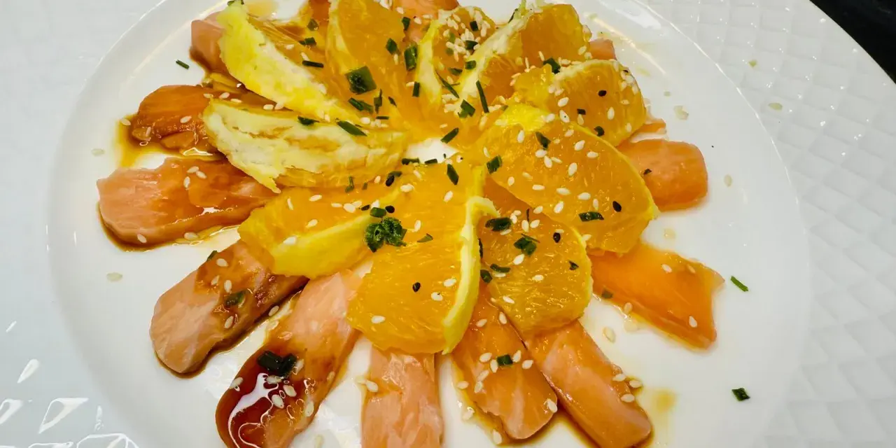 Délicieuse recette saumon cru japonaise : fines tranches de saumon cru, quartiers d'orange, sauce soja, sésame et ciboule.