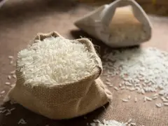 Un sac en toile de jute déborde de riz blanc, une céréale essentielle. Une autre bourse de riz est visible en arrière-plan.