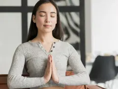 Jeune femme méditant, mains jointes, pour apprendre comment reduire le stress naturellement.