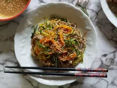 Salade de nouilles soba colorée avec des carottes, des courgettes et des graines de sésame, servie avec une sauce crémeuse.