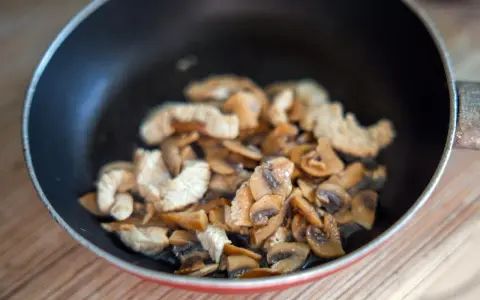 Champignons et poulet sautés dans une poêle. Une recette à éviter si vous avez une allergie champignon.