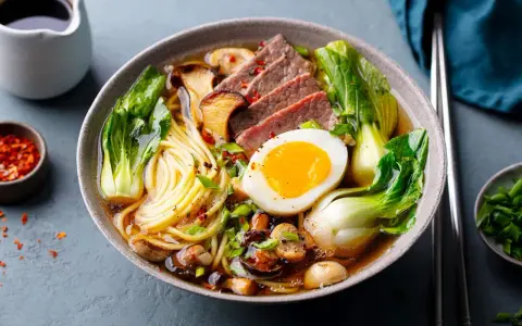 Un bol de pâte ramen savoureux avec des tranches de bœuf, un œuf mollet, des champignons et du bok choy.
