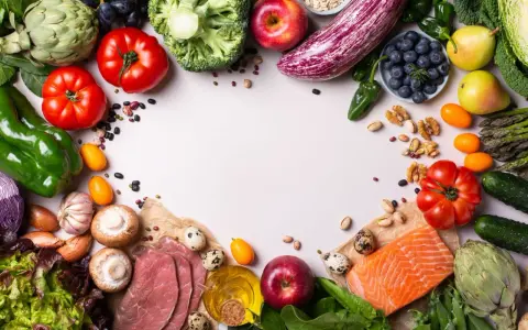 Un assortiment coloré de fruits et légumes frais, de poisson et de quelques tranches de viande, suggérant des alternatives pour remplacer la viande.