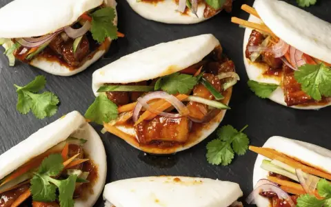 Bao nourriture : petits pains moelleux garnis de porc braisé, de concombre, de carottes et de coriandre fraîche.