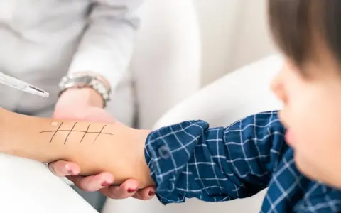 Un enfant subit un test cutané pour diagnostiquer une allergie chataigne. Des gouttes sont appliquées sur son bras marqué de lignes.