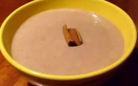 Un bol jaune contient une crème onctueuse de banane au lait de coco, garnie d'un bâton de cannelle.