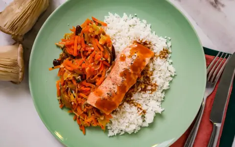 Filet de saumon nappé de sauce teriyaki, servi avec du riz blanc et une julienne de légumes croquants.