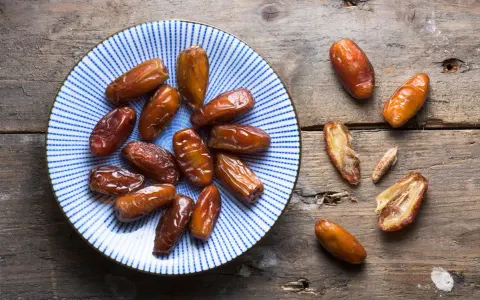 Assiette de dattes sur fond de bois. Une personne souffrant d'allergie aux dattes ne peut pas en manger.