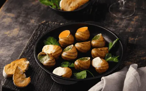 Plat d'escargots à l'ail et persil, servi avec du pain grillé. Attention, une allergie escargot peut survenir !