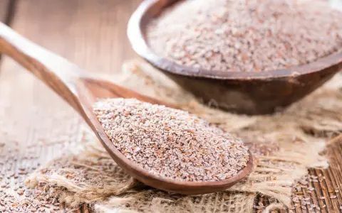 Graines de psyllium sur une cuillère en bois, un remède naturel pour un transit régulier.