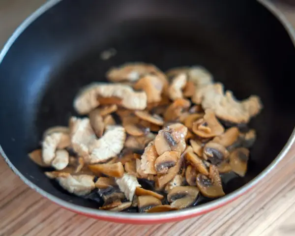 Champignons et poulet sautés dans une poêle. Une recette à éviter si vous avez une allergie champignon.