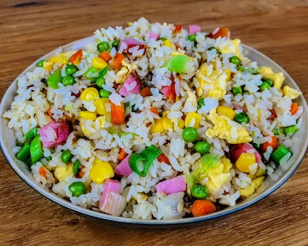 Riz cantonais coloré avec petits pois, maïs, carottes, œuf et jambon. Quelle sauce soja pour riz cantonais ? Une touche de sauce soja rehausse ce plat.