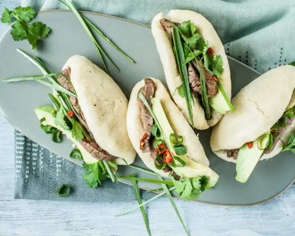 Délicieux bao buns garnis de bœuf, avocat, coriandre et oignons verts. Une recette facile pour un repas savoureux.
