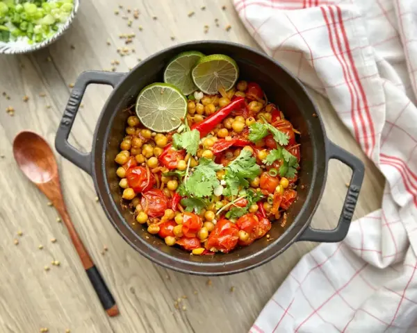 Un délicieux curry thaï végétarien aux pois chiches, tomates et coriandre, garni de quartiers de citron vert.