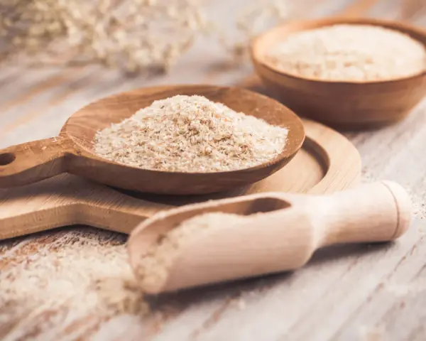 Cuillères en bois remplies de psyllium, une aide naturelle pour le transit.
