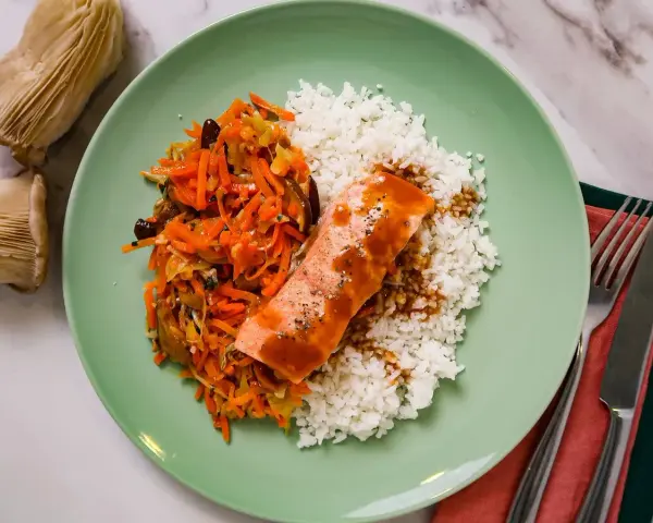Filet de saumon nappé de sauce teriyaki, servi avec du riz blanc et une julienne de légumes croquants.