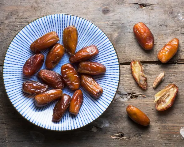 Assiette de dattes sur fond de bois. Une personne souffrant d'allergie aux dattes ne peut pas en manger.