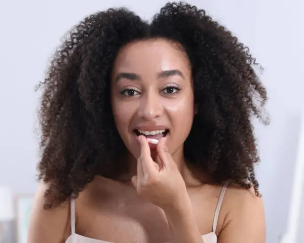 Femme aux cheveux bouclés prend une gélule. Elle se demande si le collagène marin peut causer une allergie.