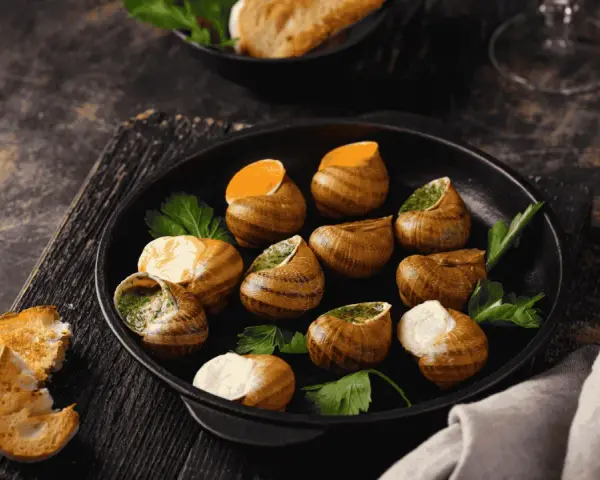 Plat d'escargots à l'ail et persil, servi avec du pain grillé. Attention, une allergie escargot peut survenir !