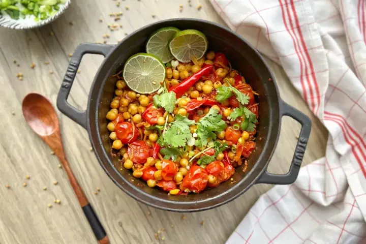 Un délicieux curry thaï végétarien aux pois chiches, tomates et coriandre, garni de quartiers de citron vert.