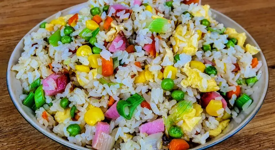 Riz cantonais coloré avec petits pois, maïs, carottes, œuf et jambon. Quelle sauce soja pour riz cantonais ? Une touche de sauce soja rehausse ce plat.