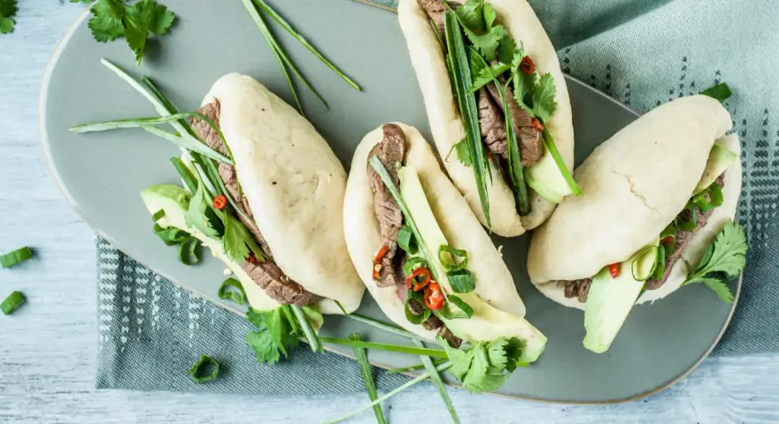Délicieux bao buns garnis de bœuf, avocat, coriandre et oignons verts. Une recette facile pour un repas savoureux.